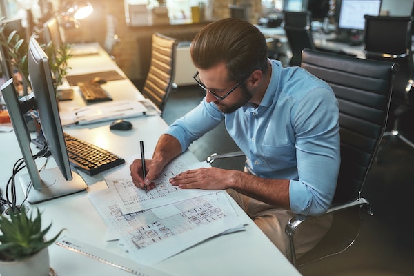 Architectural project. Successful busy bearded man in eyeglasses and formal wear drawing something while working in the office Critical incident response team
